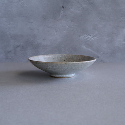 Side view of the handmade ceramic plate, showing its gently flared rim and slightly elevated foot.