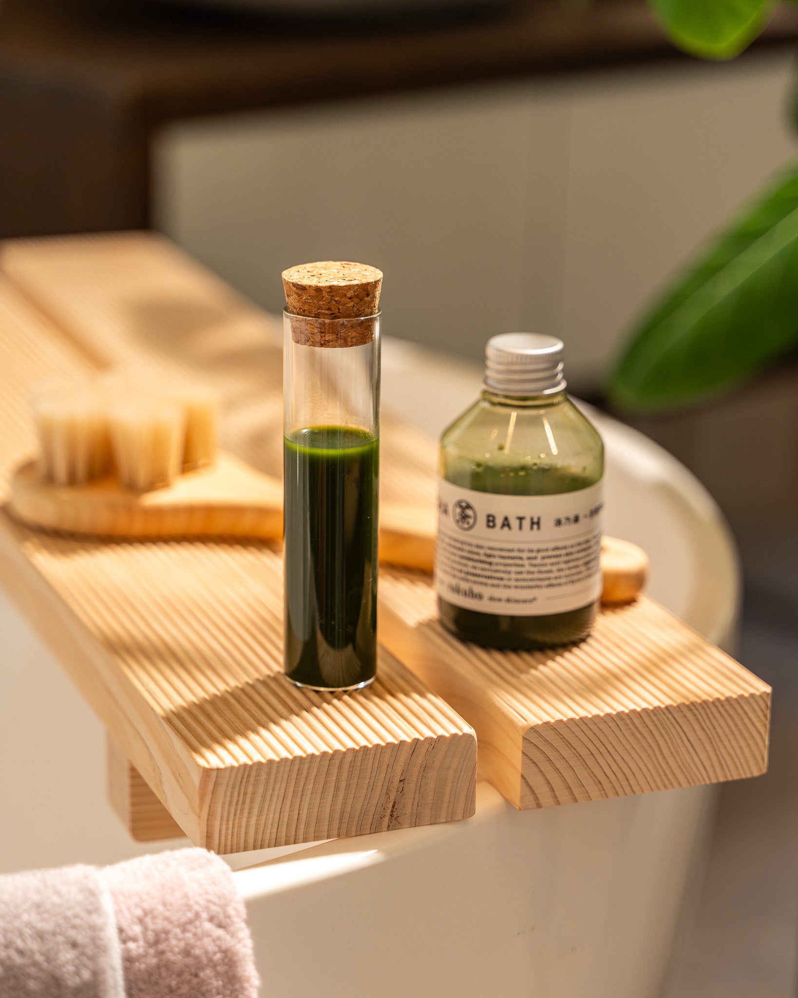 Two bottles of bath products on a wooden bath tray with a blurred background