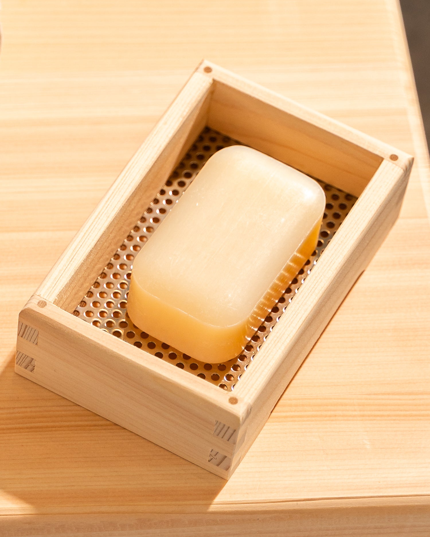 Bar of soap in a wooden soap dish on a wooden surface