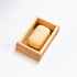 Bar of soap in a wooden soap dish on a wooden surface