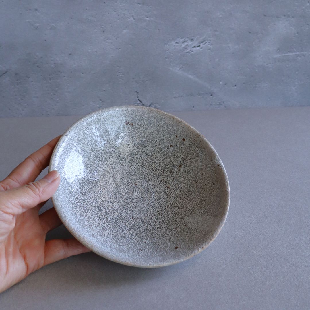 A person holding the plate to show its size and organic surface finish in natural light.