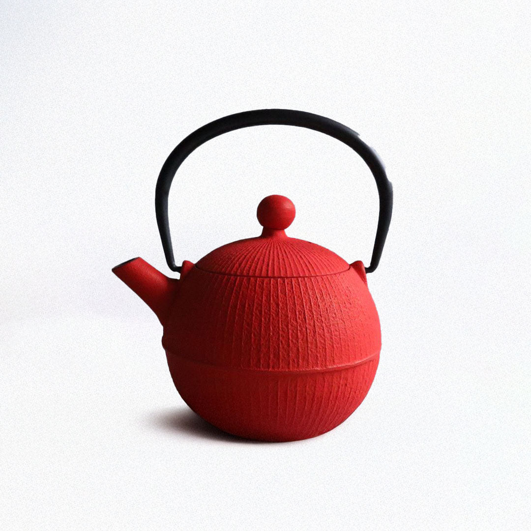 A vibrant red Nambu Tekki teapot, shaped like a traditional Japanese temari ball. The teapot features a black handle and a distinctive design, set against a light gray background.