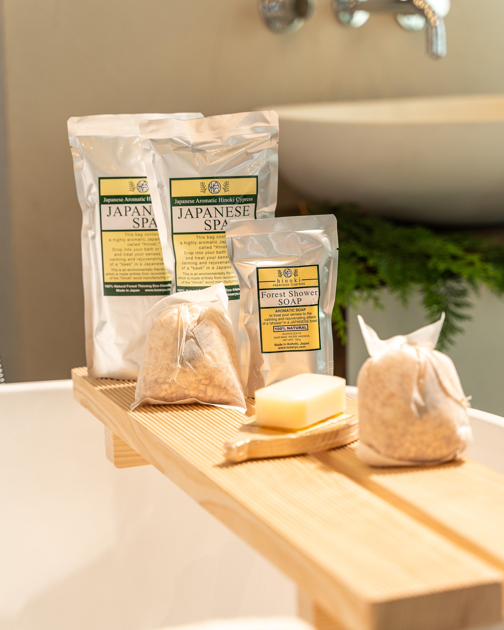 Japanese Spa products including soap and bath pouf on a wooden tray with a bathtub in the background.