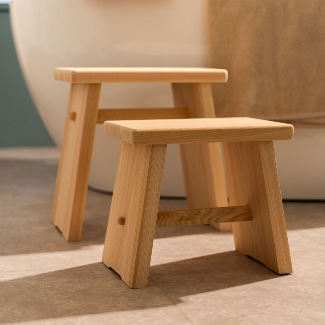 Two wooden bathroom stools on a tiled floor with a blurred background