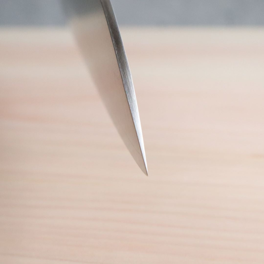 A close-up shot of the sharp blade edge of a Japanese Santoku knife, emphasizing the precision and sharpness of the blade.