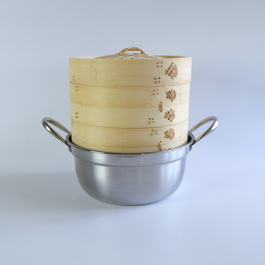 Bamboo seiro steam basket stacked on a stainless steel pot, fully assembled with the woven bamboo lid on top.