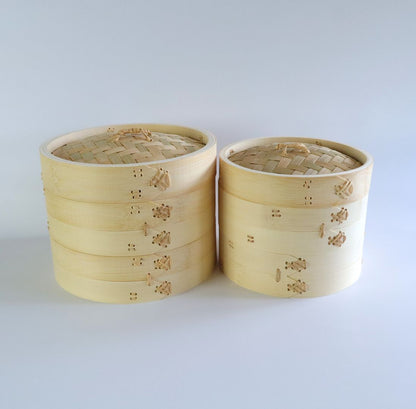 Two bamboo seiro steam baskets, each with two tiers, placed side by side. The baskets feature rattan fasteners and bamboo lids.