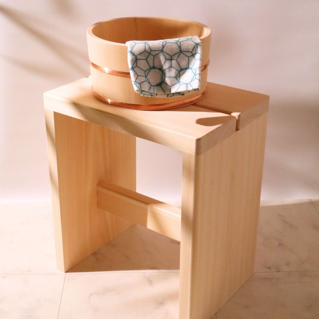 Wooden stool with a woven basket on top against a neutral background