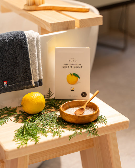 Bath salt packaging with a lemon and wooden spoon on a wooden stool.