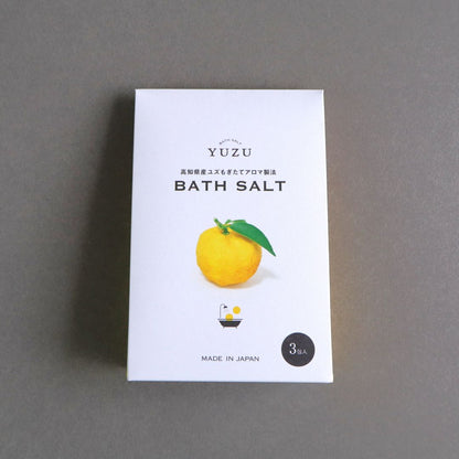 Close-up of Yuzu Bath Salt packaging featuring a bright yellow yuzu illustration on a white background. Text reads "YUZU BATH SALT - Made in Japan."

