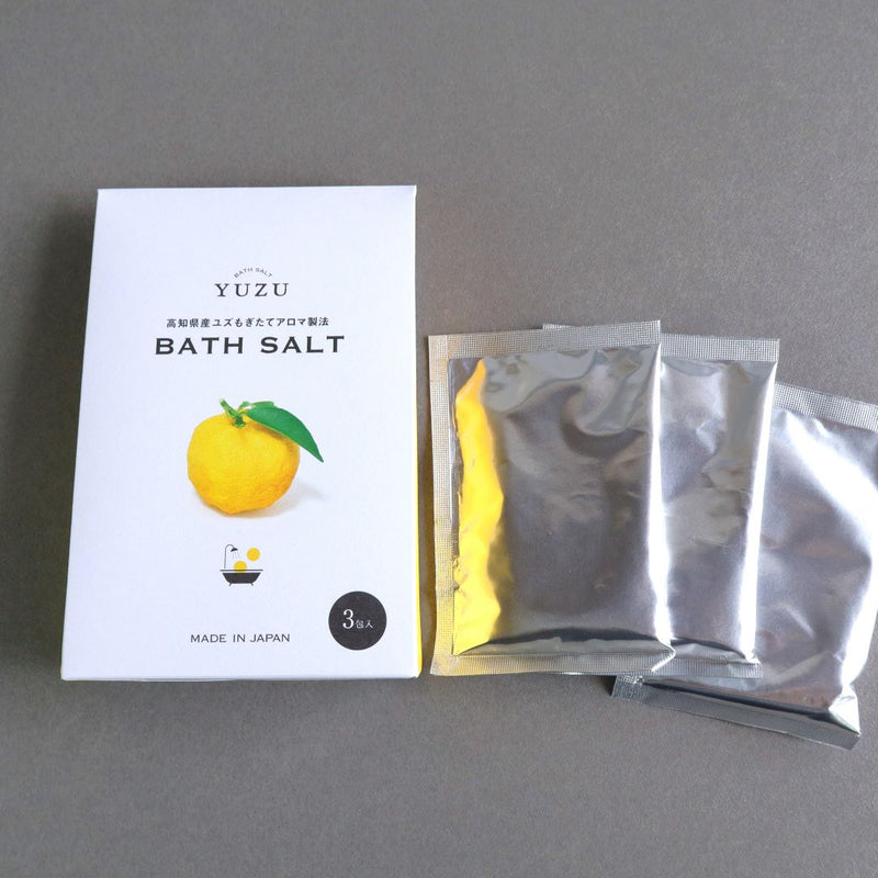 Yuzu Bath Salt box displayed with three silver sachets beside it, showcasing the individual packets of bath salt included inside the box.