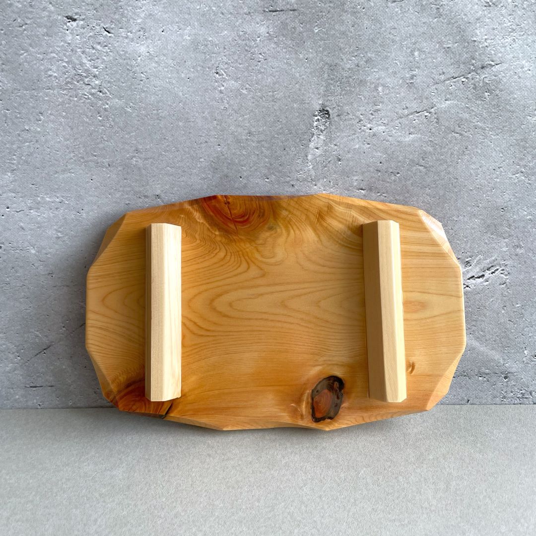 In a grey room, the back of a wooden sushi tray