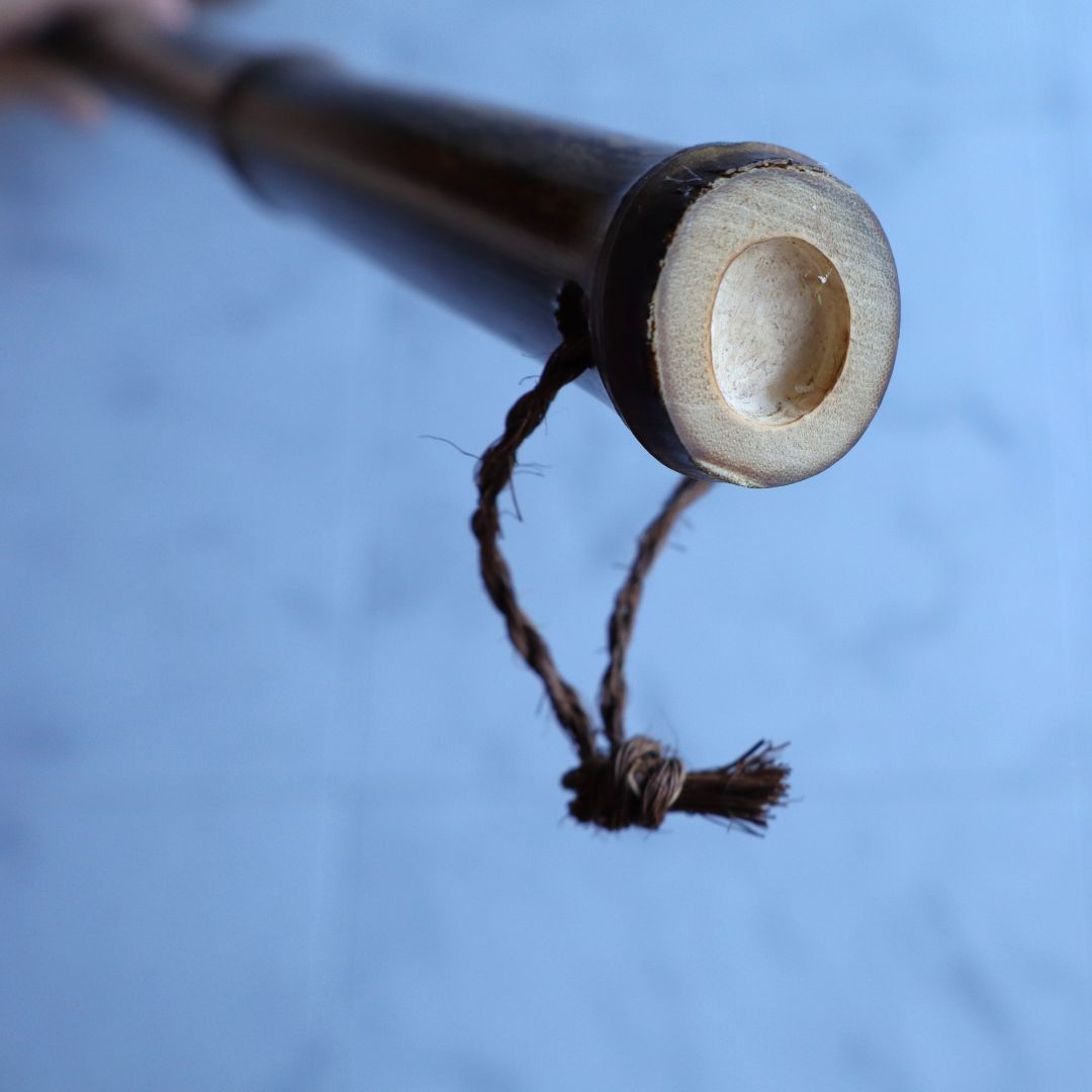 Close-up of the end of a bamboo broom handle with a natural fiber loop threaded through.