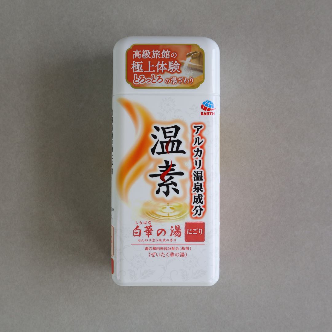 A bottle of Onso Shiraha no Yu Bath Salts with a white and orange design, featuring Japanese text highlighting its alkaline hot spring ingredients for a luxurious onsen experience.