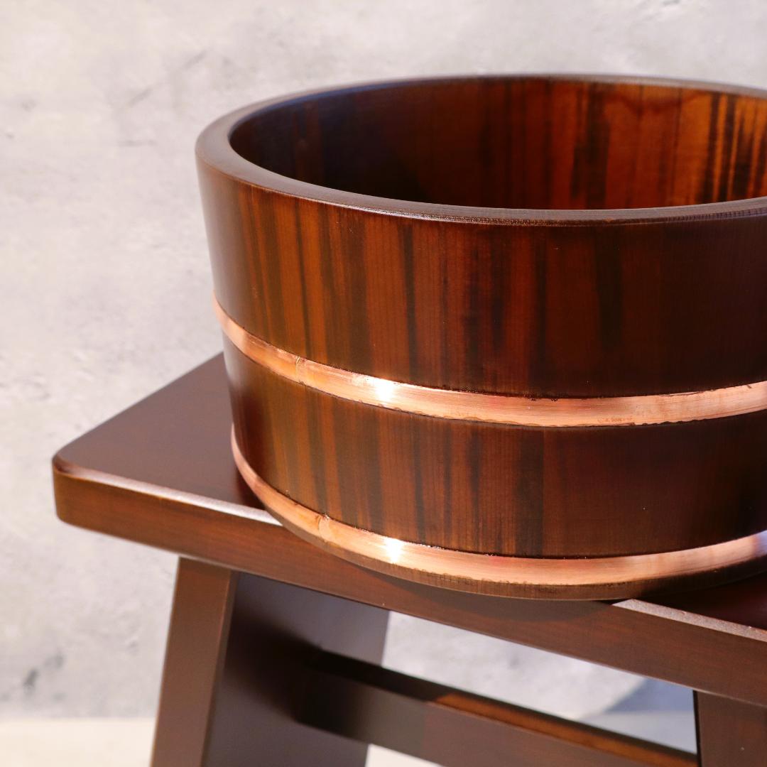 Wooden barrel with a copper band on a wooden stand against a light background