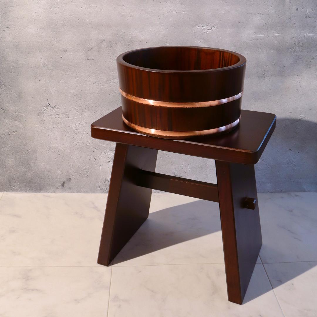Wooden stool with a circular wooden bowl on a concrete floor and wall background