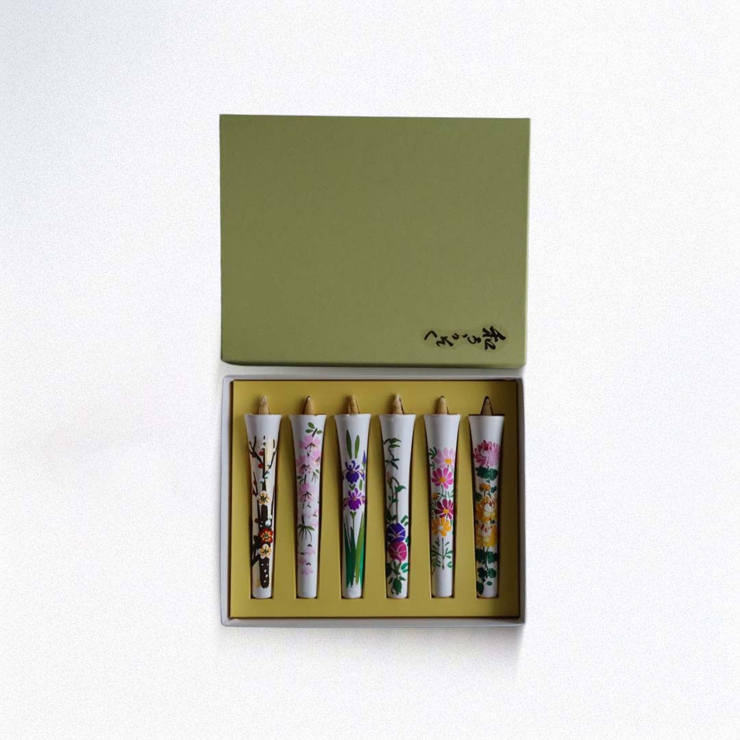Set of five floral-patterned candles in a green box on a white background