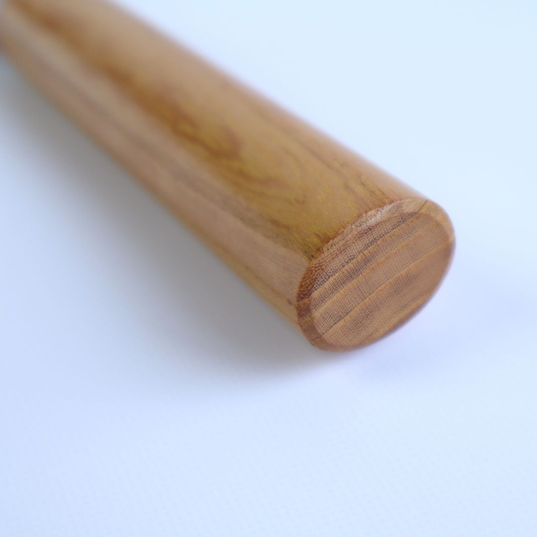  A close-up of the cylindrical end of a honey-toned wooden knife handle, displaying intricate grain patterns and a smooth finish, set against a soft white background. The natural lines and gentle polish of the wood emphasize the craftsmanship and quality of the handle.