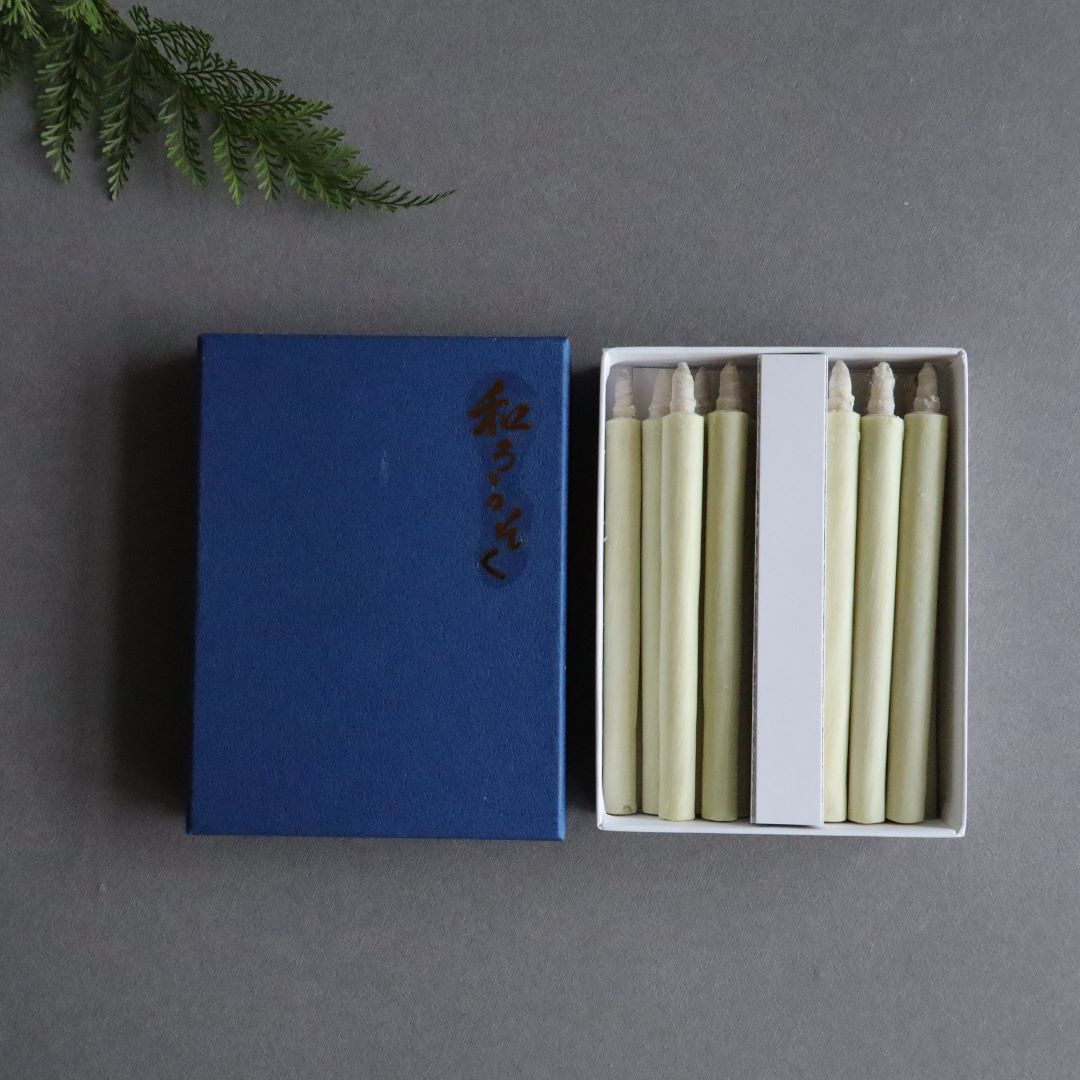 A set of twelve organic taper candles made of authentic Japanese sumac wax, each measuring 11cm (4.3 inches) in height, presented neatly in an open white box with a blue lid adorned with Japanese characters.