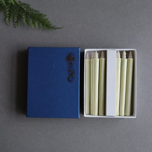 A set of twelve organic taper candles made of authentic Japanese sumac wax, each measuring 11cm (4.3 inches) in height, presented neatly in an open white box with a blue lid adorned with Japanese characters.