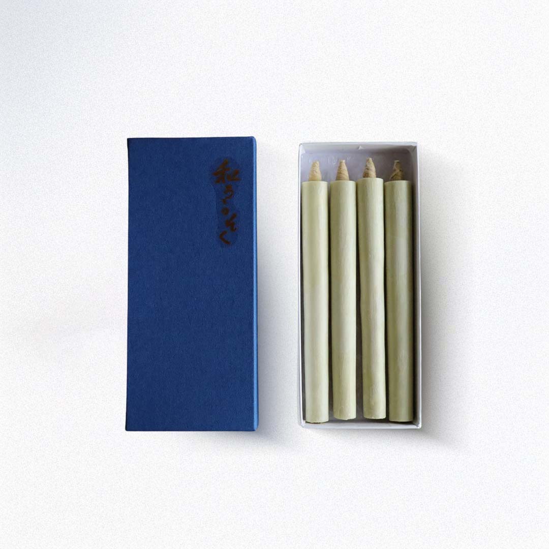 Set of four green candles in a white box with a blue box featuring a logo on a white background