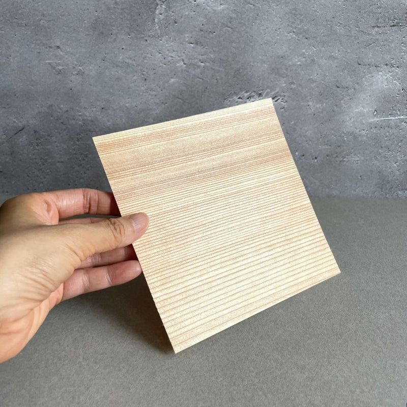 A person's hands securely holding a wooden cooking sheet in a modern grey-toned kitchen.