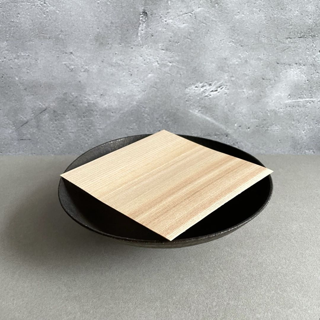 A wooden sheet on a ceramic plate in a grey room