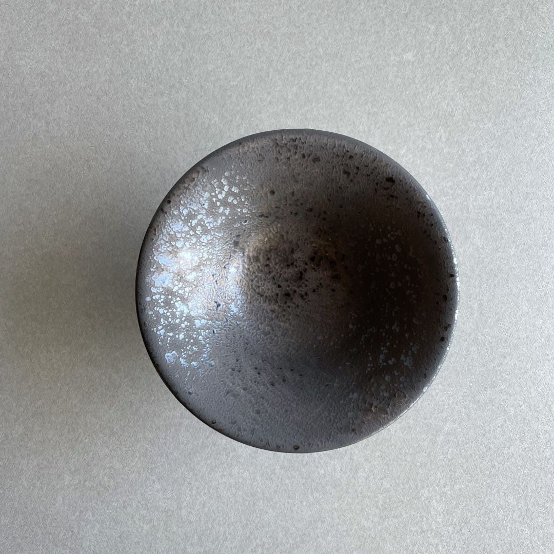 Top view of a black ceramic round plate placed on a grey table.