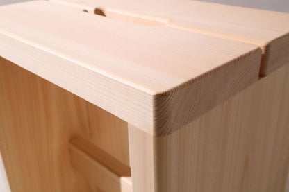 Close-up of a wooden stool with a light brown finish.