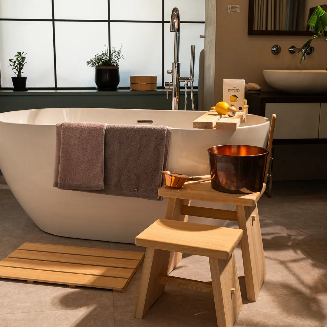 Bathroom with a freestanding bathtub, wooden stool, and decorative items.