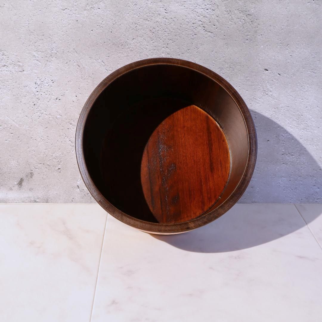 Wooden bowl with a dark interior and wooden lid on a light gray surface