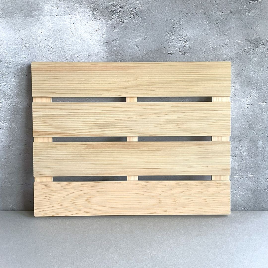 A wooden board with horizontal slats and gaps on a grey concrete background.