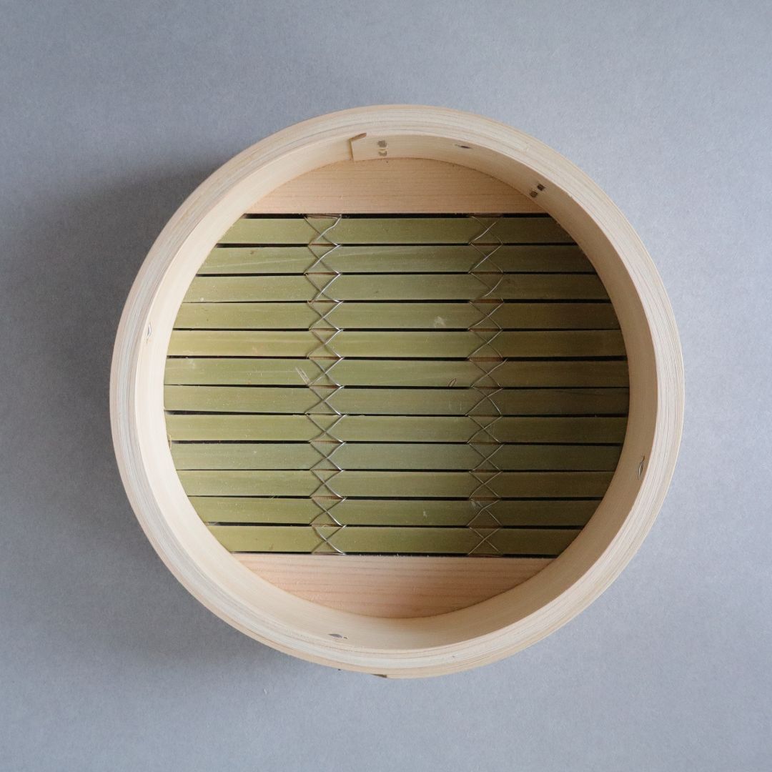 Wooden basket with green woven interior on a gray background