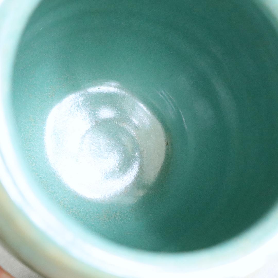 Close-up of the interior of a handmade Japanese ceramic jar, showcasing its smooth, glossy retro green glaze.