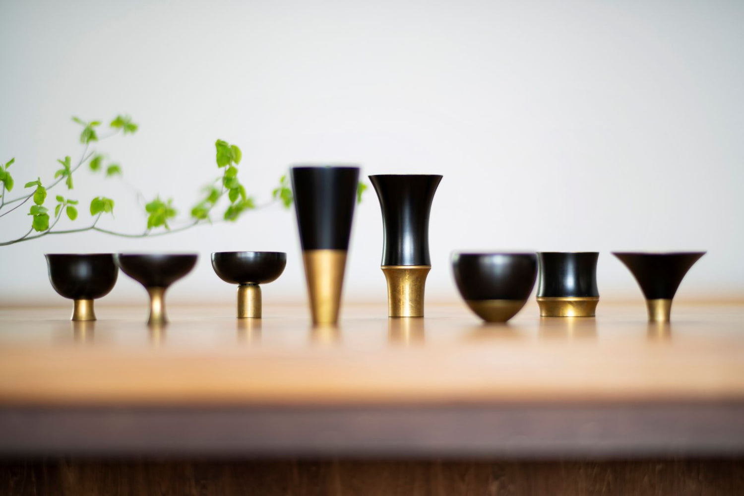 Set of black and gold sake cups on a wooden surface with a blurred background