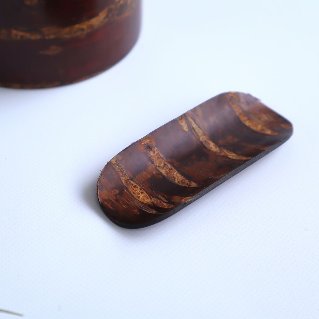 A shallow, elongated wooden dish with a rich, dark finish and visible grain and texture from the cherry bark, positioned against a white background with a slight shadow indicating its raised profile.