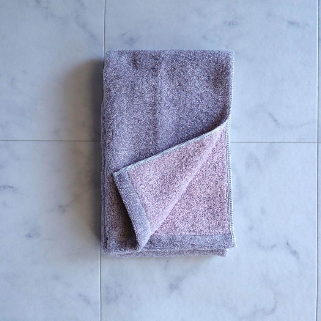 Imabari reversible towel in sakura pink and grey, neatly folded on a marble surface, showcasing its soft texture and high-quality craftsmanship from Japan.