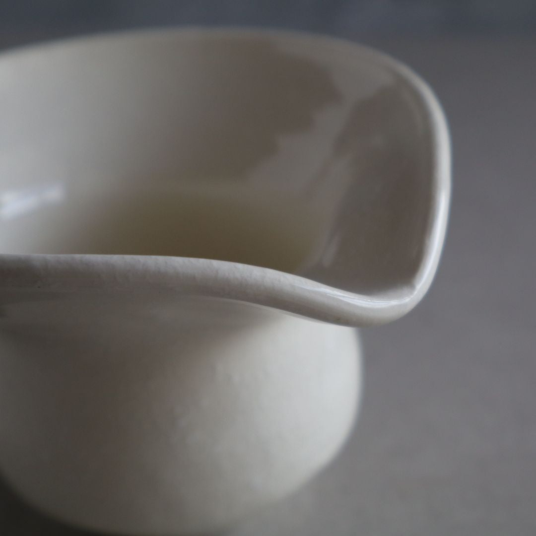 Close-up of a white ceramic pitcher on a gray background