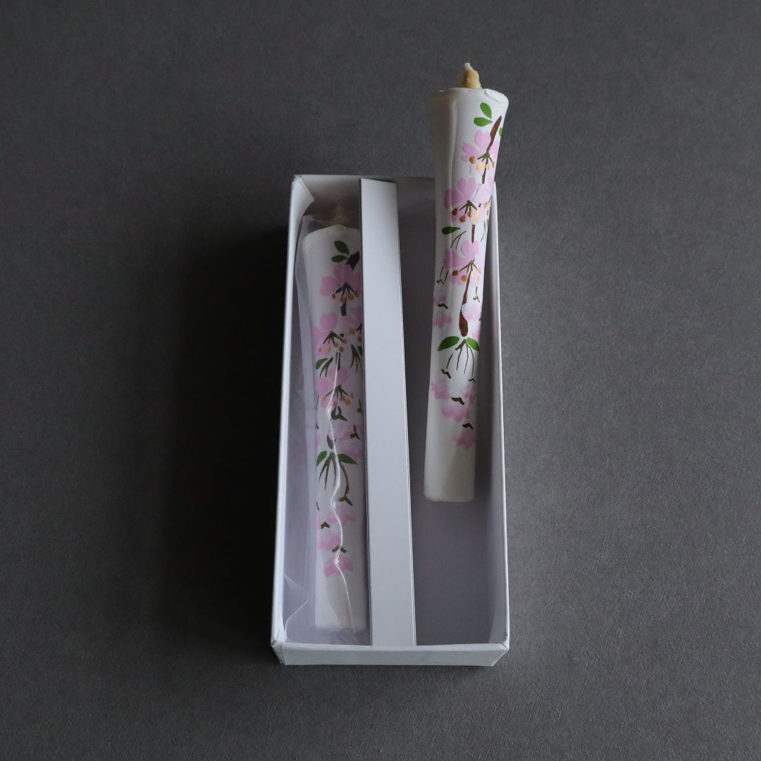 Top-down view of two hand-painted cherry blossom Japanese rice bran wax candles in a white presentation box on a grey background, ideal for an artisanal and organic home decor experience.