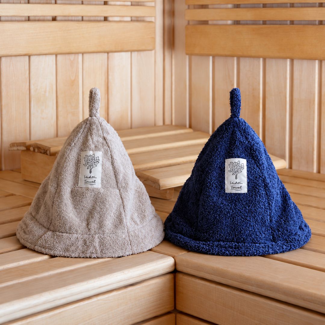 Two textured knit sauna hats, one in beige and one in navy blue, displayed on wooden sauna benches.