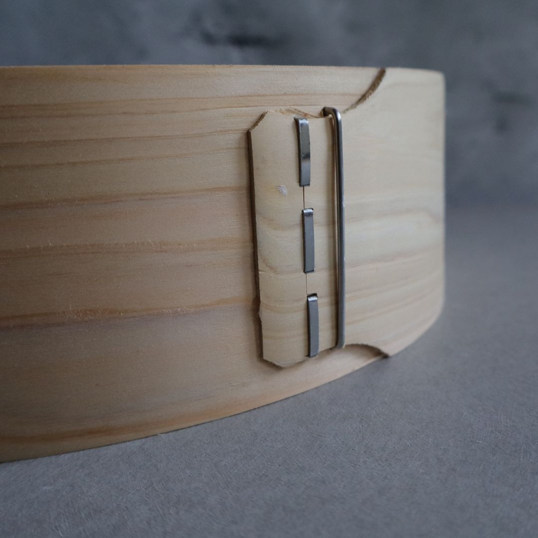 Close-up of a wooden object with a metallic hinge on a gray background