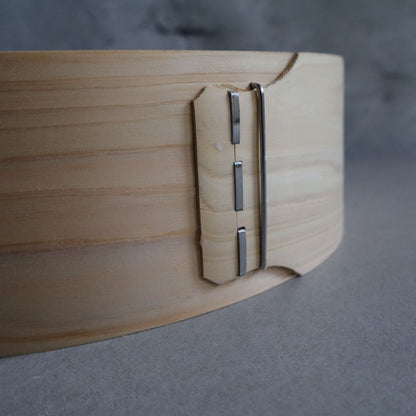 Close-up of a wooden object with a metallic hinge on a gray background
