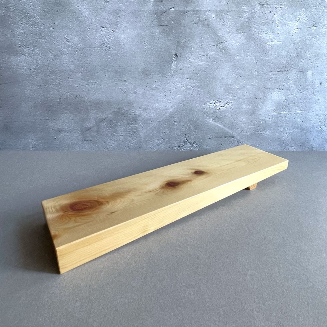 In a grey room, a wooden sushi tray with a rectangular shape.