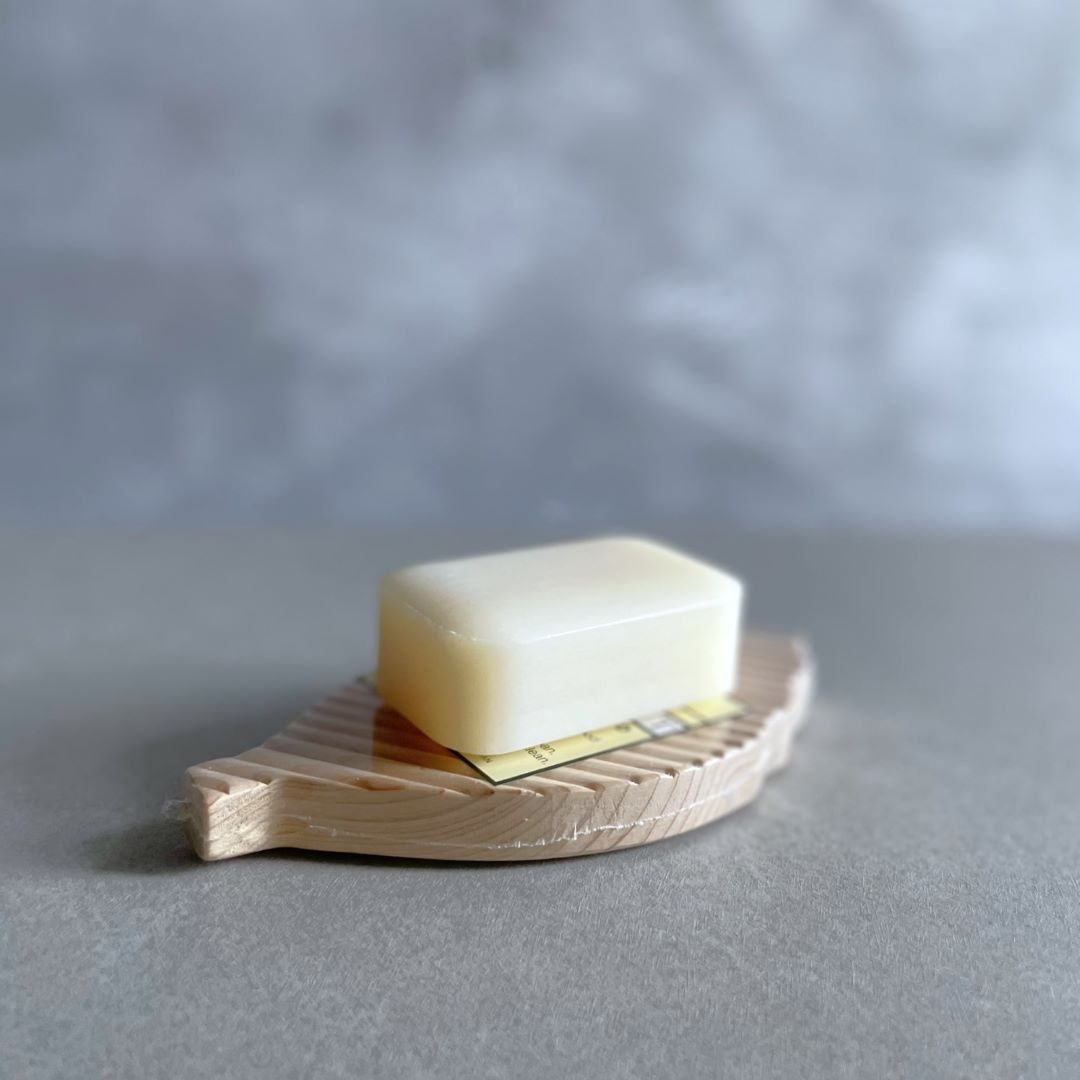 a hinoki soap on a wooden soap dish in a grey room.