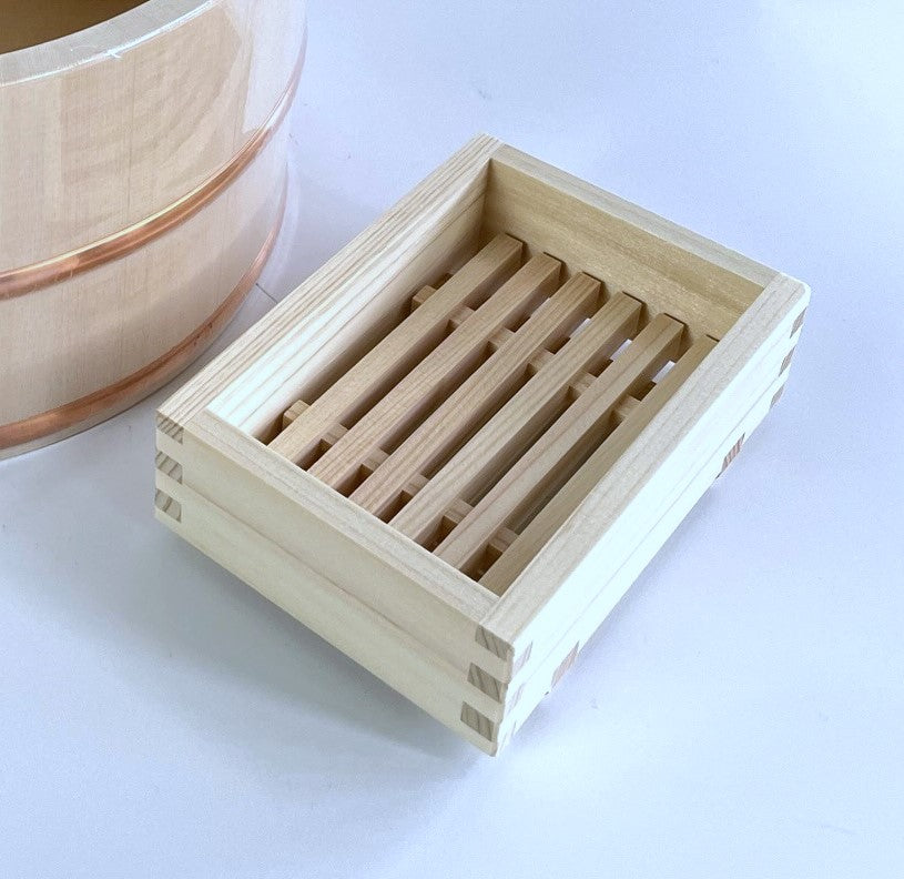 A wooden soap stand on a white floor with a notice next to it