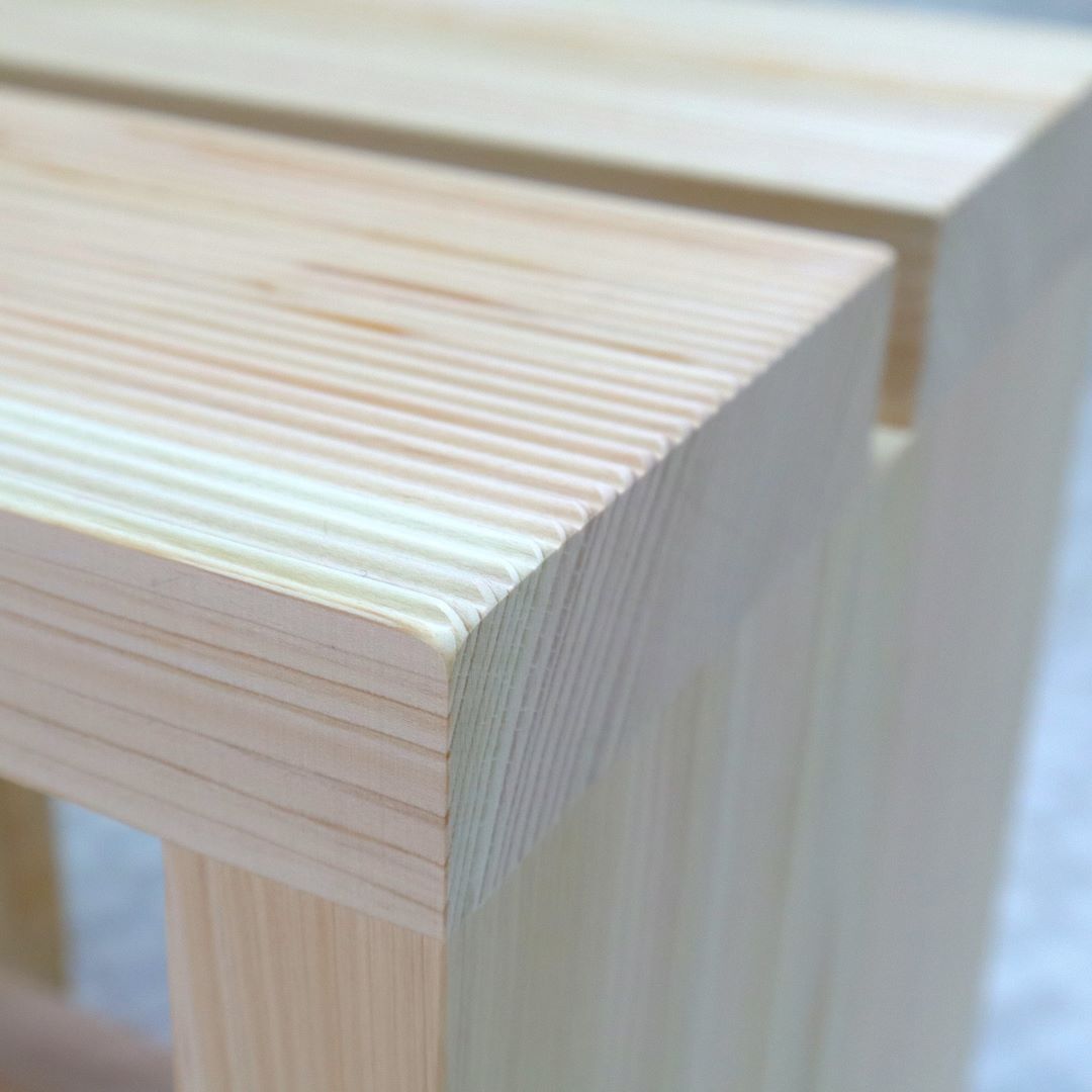 Detailed view of a Hinoki wood bath chair&amp; corner, showcasing the fine wood grain and smooth finish of the pale, high-quality cypress.