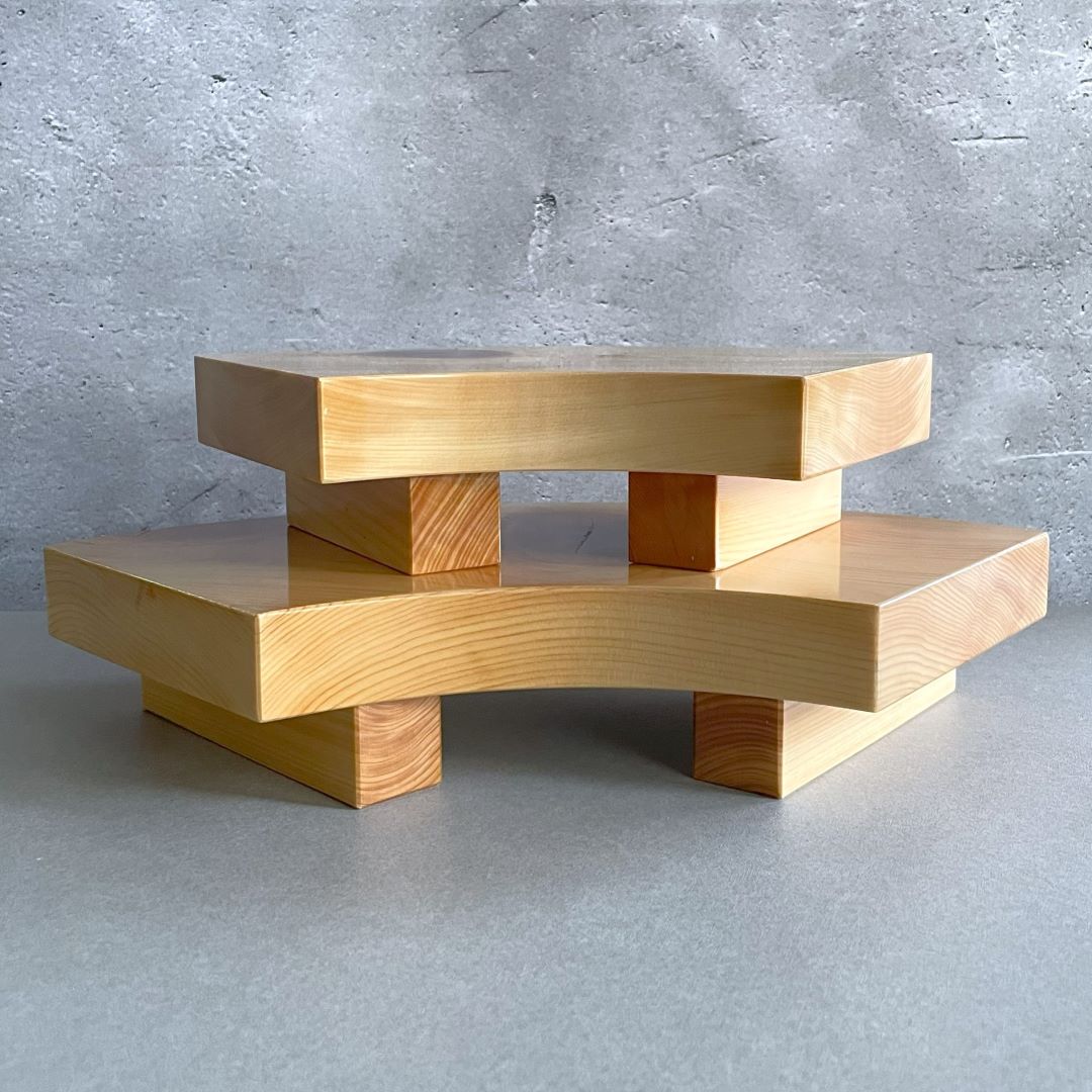 Two stacked wooden sushi serving trays with a smooth finish and visible wood grain, designed in a staggered, step-like formation, displayed against a grey concrete textured background.