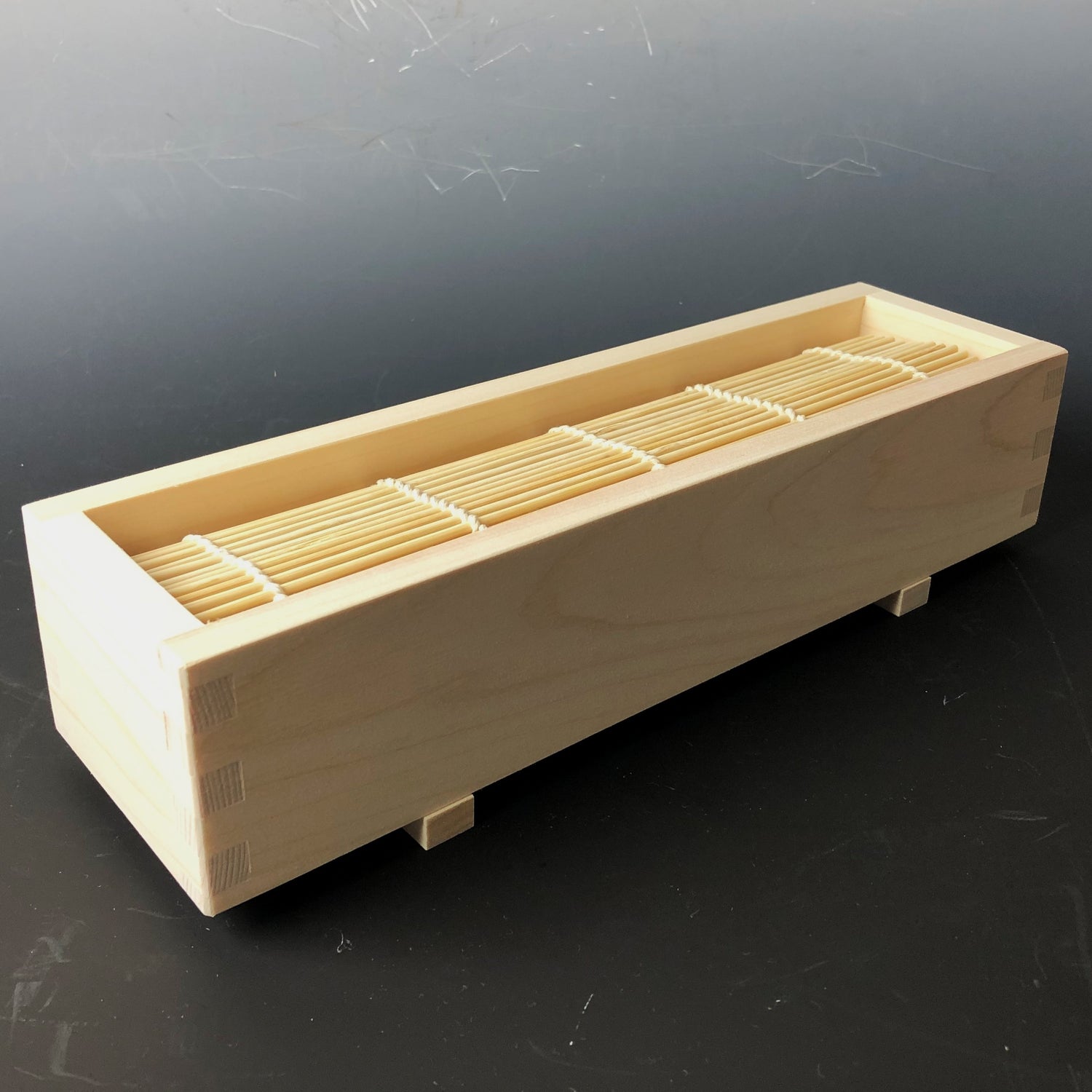 Wooden box with compartments containing wooden sticks on a dark background