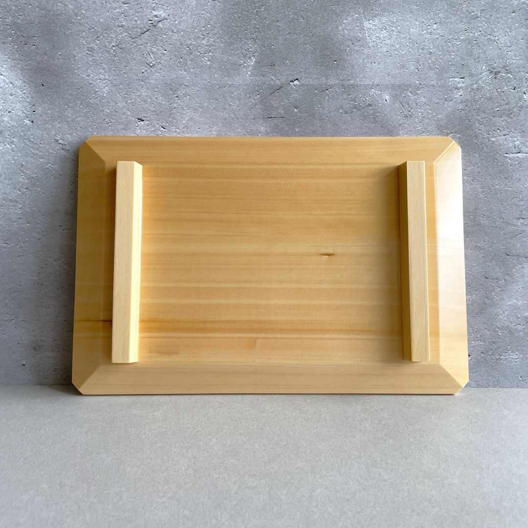 On a grey surface, a wooden backward sushi tray with wooden feet on it