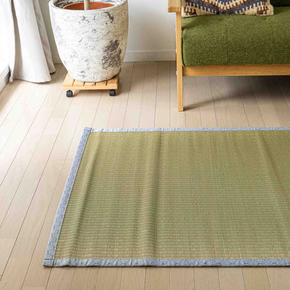 gray tatami placed on the floor in front of a green wooden sofa